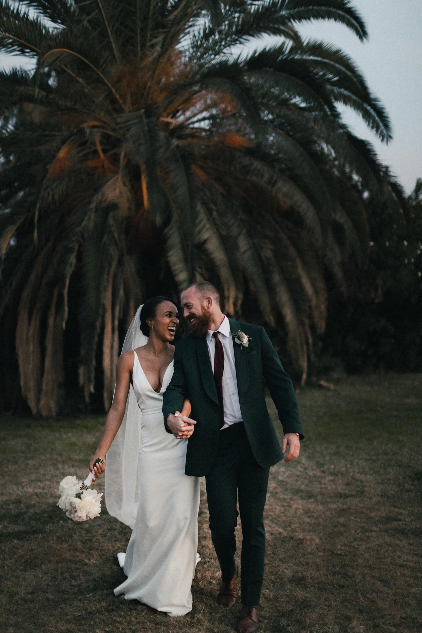 Couple in sleek wedding attire at twilight, moody editorial lighting
